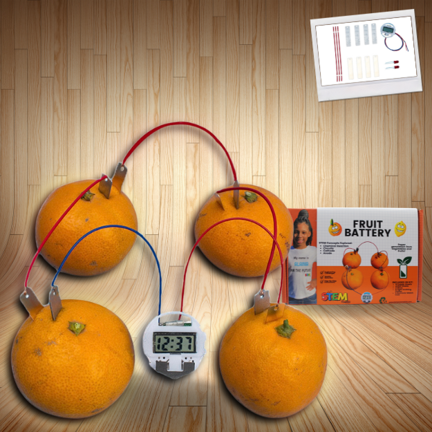 Assembled Fruit Battery STEM Kit featuring oranges connected with wires, an LCD clock powered by the fruit, and the product packaging on a wooden background.