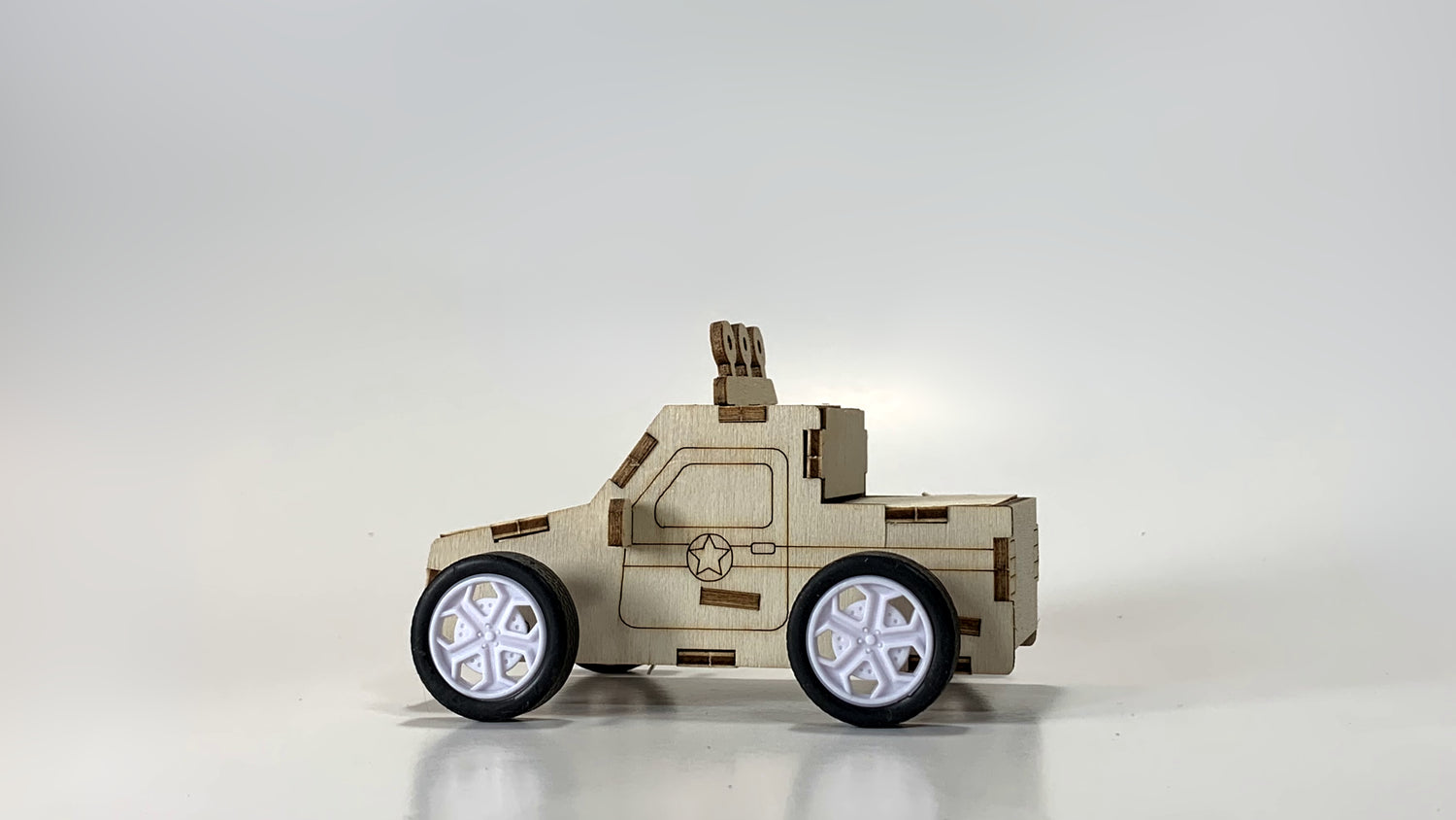Side view of the Pull-Back Race Car STEM Kit, featuring a wooden body, star emblem, white-rimmed wheels, and detailed laser-cut design