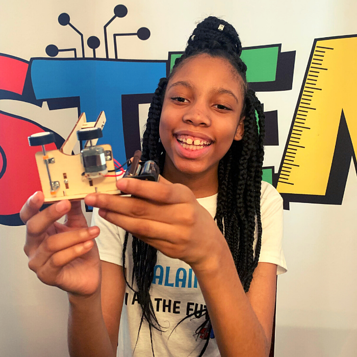Alaina Davis, Co-Owner and CEO of STEM Powered Kits, showing the side view of the Ball Pitching Machine STEM Kit, designed for hands-on STEM learning.