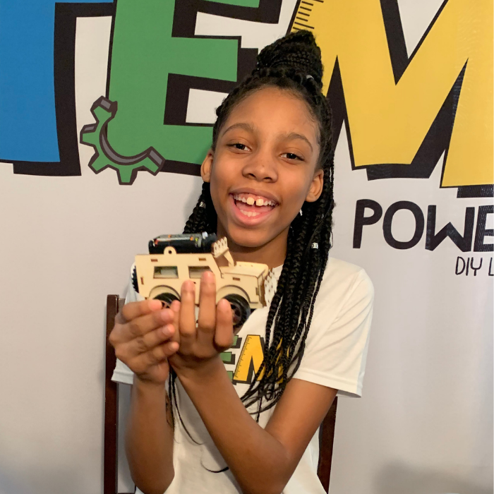 Alaina Davis, Co-Owner and CEO of STEM Powered Kits, proudly holding the Electric Wired Jeep STEM Kit, designed for hands-on learning and creative exploration.