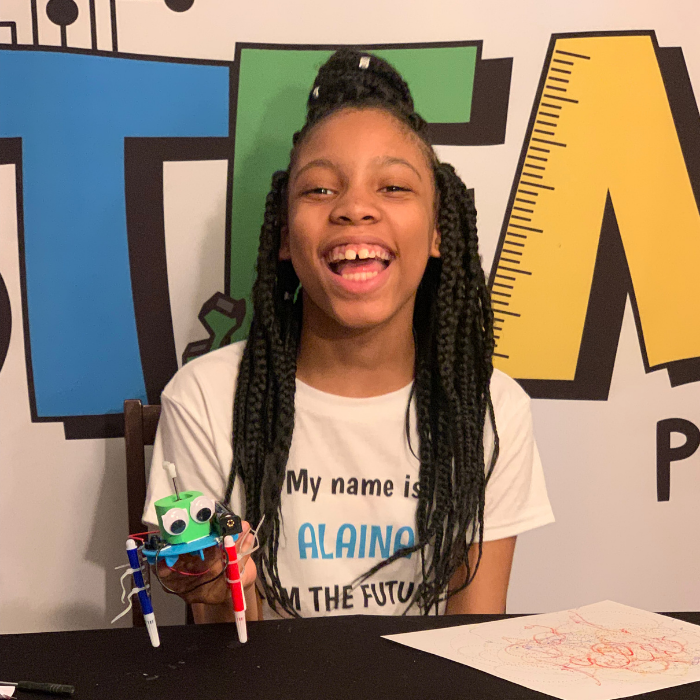 Unassembled components of the plastic version of the Graffiti Robot STEM Kit, including markers, battery holder, motor, screws, and colorful design parts.