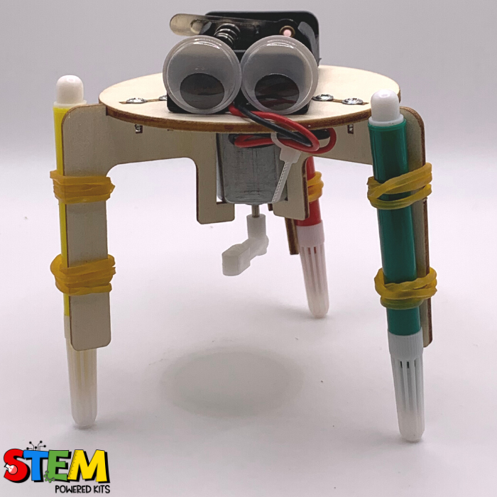 Close-up front view of the wooden Graffiti Robot, highlighting its googly eyes, motor, and colorful marker legs designed for STEM experiments.